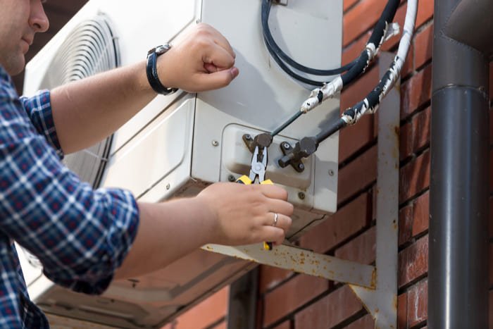 man-repairing-air-conditioning-unit-on-brick-wall-2026-09-23-05-44-45-utc (1)